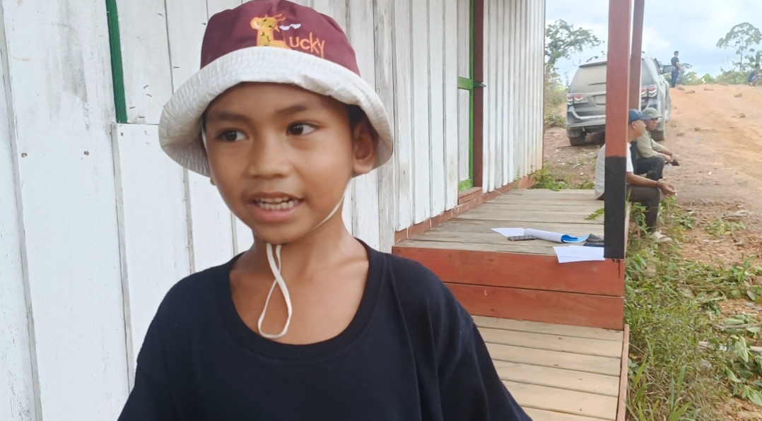 Keterangan Foto : Eno, bocah kecil yang biasanya ceria, tampak sedih saat menunjukkan lokasi kebun yang dulu ditanam bersama mendiang ayahnya. Kepada awak media ia berkata, “Saya sedih, dulu di sini kami berdua sama Bapak tanam karet, tapi sekarang sudah tidak ada, habis digusur PT NPR,” (Dok. Trackperistiwa.com/Henryanus Achiang).
